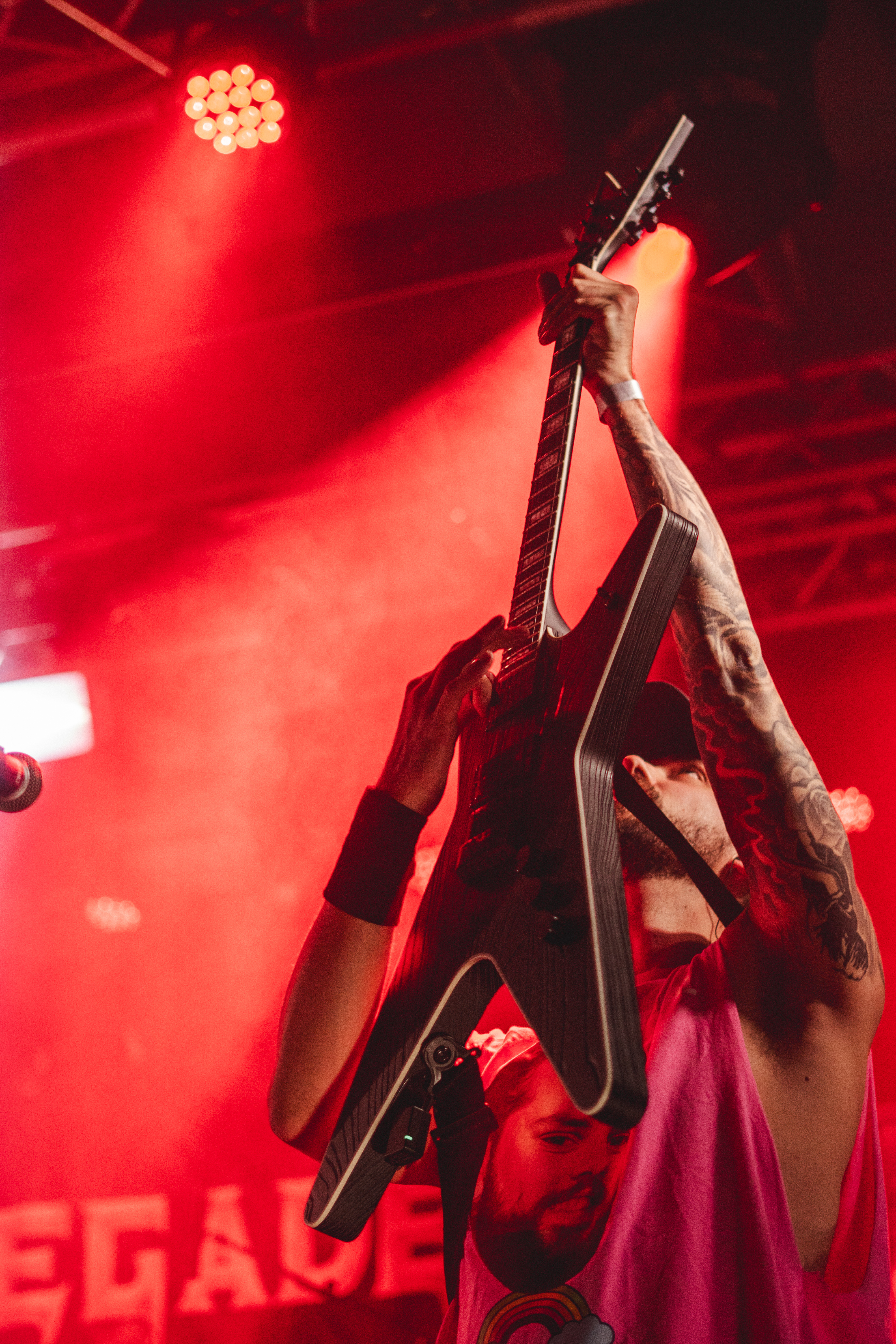 Guitarist holding a guitar overhead in red stage light